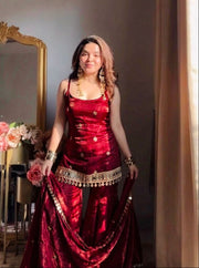 Woman in a red dress standing in a room with a decorative mirror and flowers.